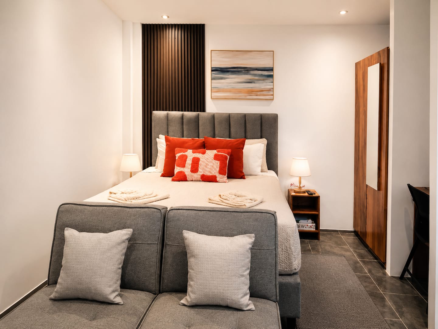 Monarca’s queen bed, warm wood finishes, and reading sofa